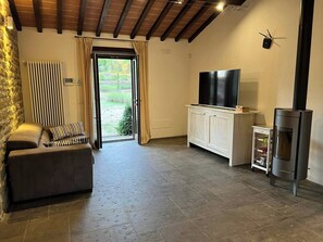 Ein Wohnzimmer mit Sofa, Fernseher, Kamin und Blick durch eine Tür.