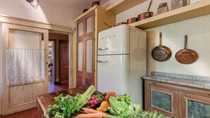 Une cuisine avec une table en bois, un réfrigérateur blanc et des ustensiles de cuisine en cuivre.