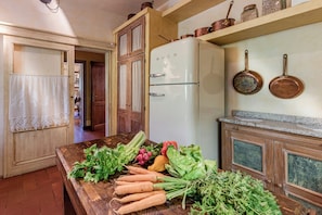 Eine Küche mit einem Holztisch, einem weißen Kühlschrank und Kupferkochgeschirr.