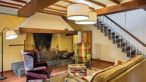 Un salon chaleureux avec une cheminée, un escalier et une grande fenêtre.