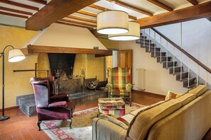 Ein gemütliches Wohnzimmer mit Kamin, Treppe und großem Fenster.