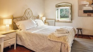 Une chambre à coucher avec un lit, des tables de chevet, une fenêtre et un radiateur.
