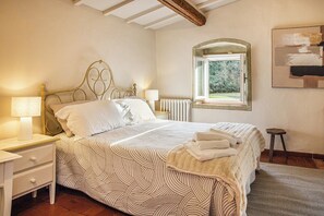 Ein Schlafzimmer mit einem Bett, Nachttischen, einem Fenster und einer Heizung.