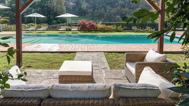 Un espace extérieur abrité comprenant une piscine, des chaises longues et une pergola.