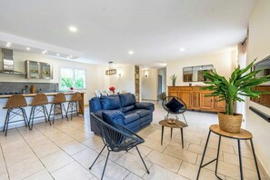 Eine moderne Küche mit Essbereich, einem blauen Sofa und einem Blumentopf.