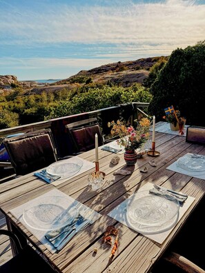 A wooden dining table set outdoors with plates, cutlery, and candles. - Historic timber cottage from 1700s on Hamburgö (Hamburgsund)
