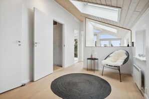 A modern interior with a skylight, a round rug, a chair, and a mirror reflecting the outdoors. - Sea view holiday home near Ebeltoft (Ebeltoft)