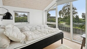 A bedroom with a bed, a window, and a view of the outdoors.