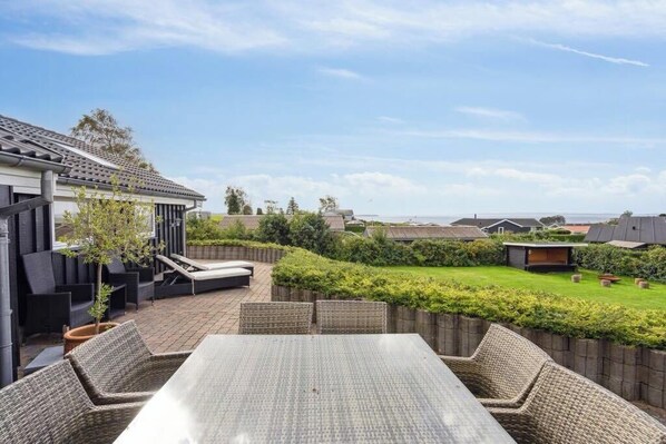 Un patio con una mesa y sillas, un espacio de estar techado y vistas al barrio circundante.