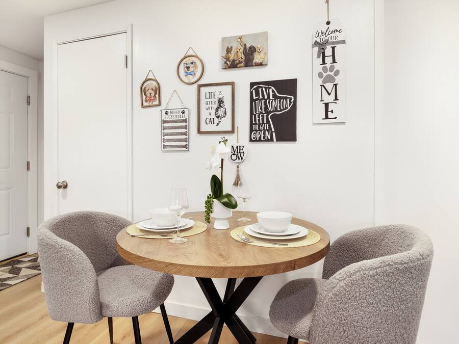 Un comedor con una mesa redonda de madera, dos sillas grises y una puerta blanca al fondo.
