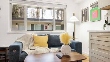 Una sala de estar con sofá, mesa de centro, lámpara y cómoda.