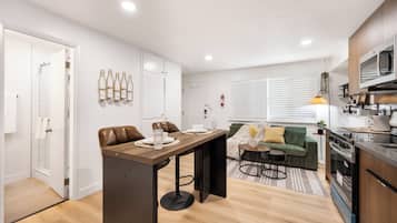 A modern kitchen with a dining area, a sofa, and a small table.