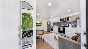 A modern kitchen with white cabinets, a microwave, and a stove. There is a dining area with a table and chairs. - STAYOO SUITES-Seattle Secret Garden (Seattle)