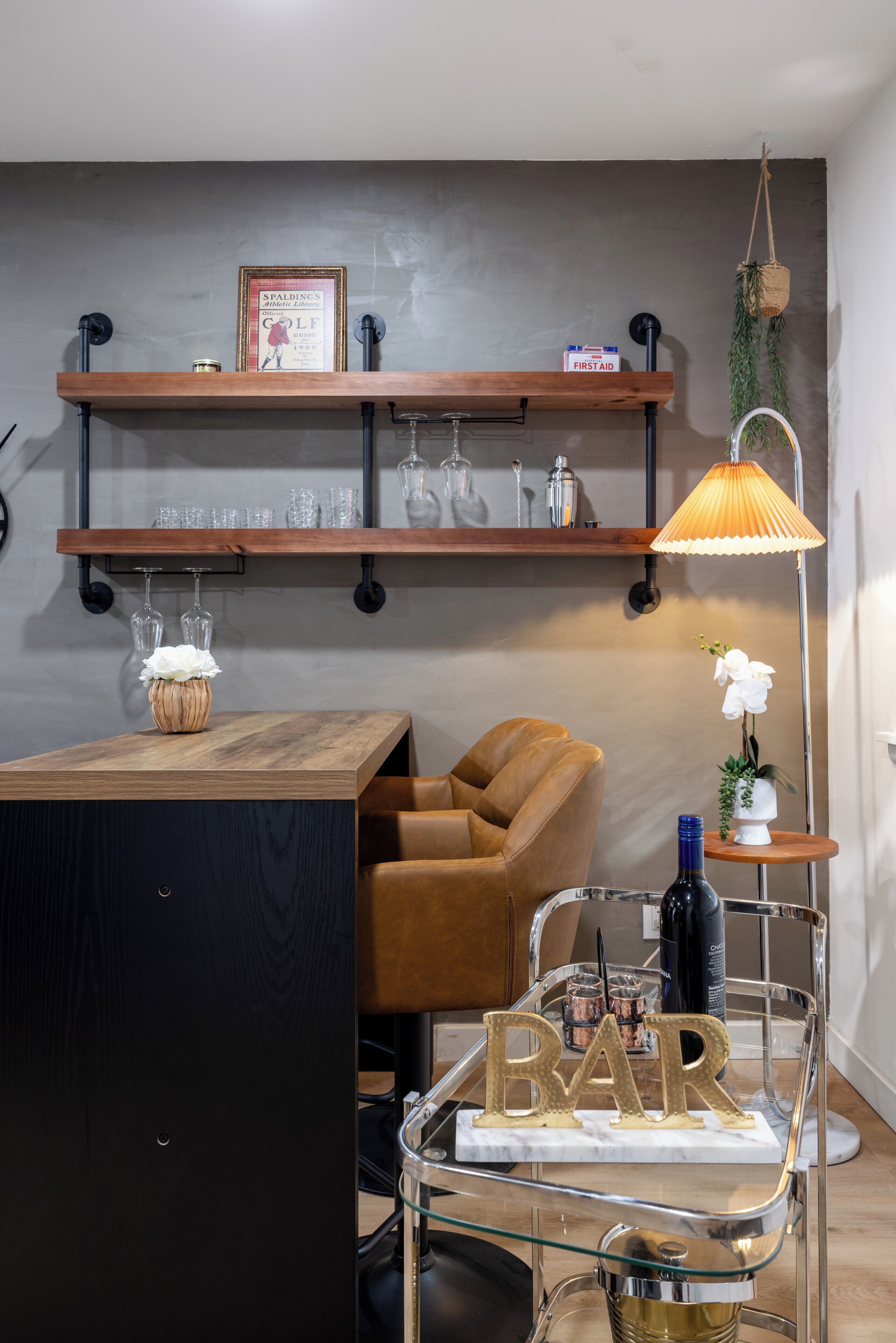A modern living space with a wooden bar area, a sofa, a hanging plant, and a lamp.