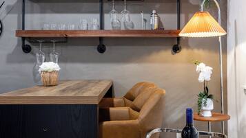 A modern living space with a wooden bar area, a sofa, a hanging plant, and a lamp.