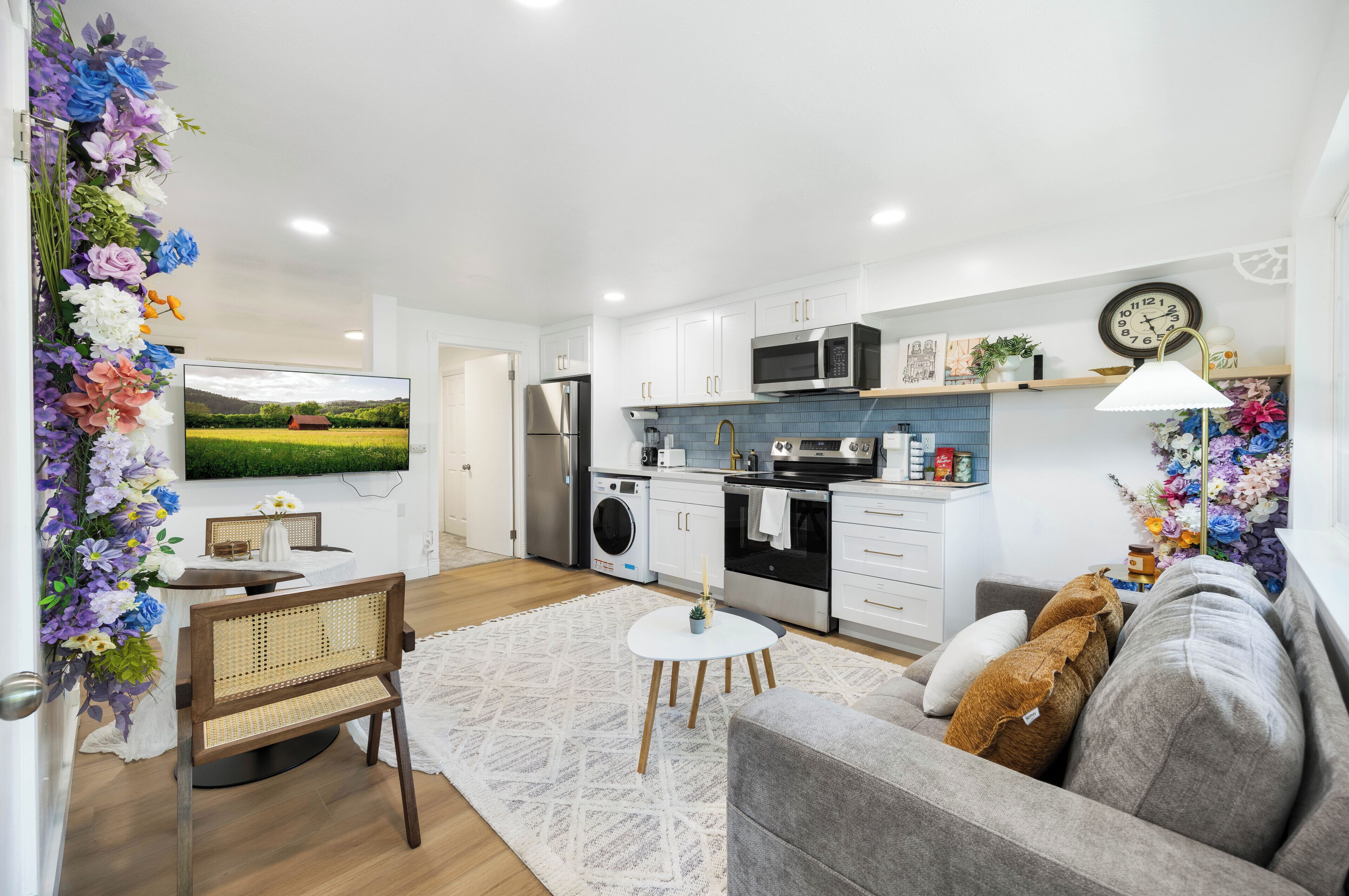 A modern kitchen with white cabinets, a microwave, and a clock on the wall.