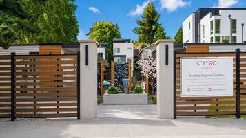 A gated entrance to a modern building with a sign for Stayoo Suites Seattle Secret Garden.