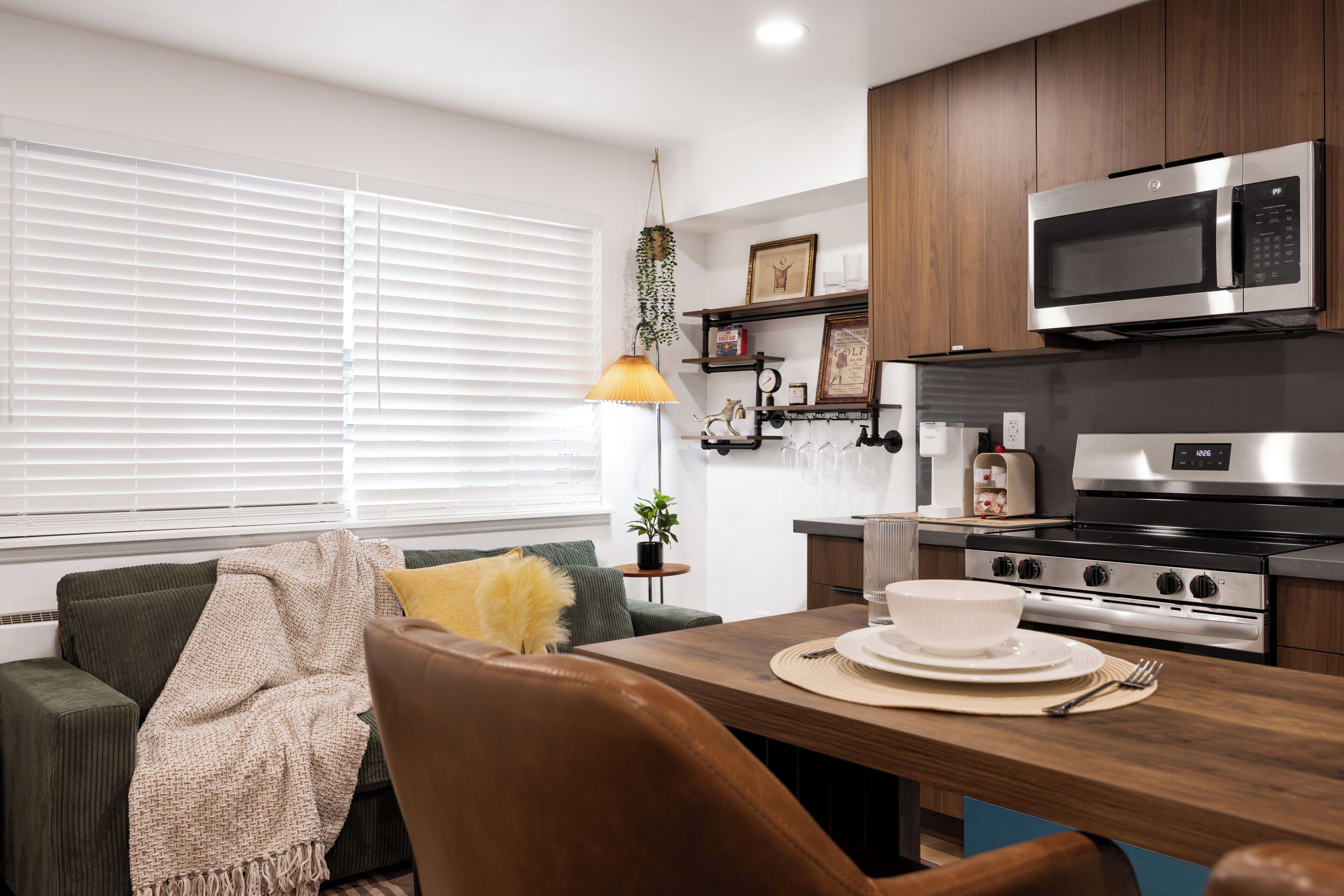 Una cocina moderna con armarios de madera, un microondas, un horno y una mesa de comedor con platos y cubiertos.