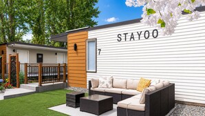 A Stayoo branded outdoor seating area with a sofa, two side tables, and a small coffee table. - STAYOO SUITES-Seattle Secret Garden (Seattle)