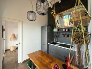 A modern kitchen with a wooden table, hanging pendant lights, and a mirror above the sink. - Panoramic villa with sunset and sea view (Pollina)