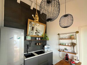 A compact kitchen with a refrigerator, a sink, a toaster, and a microwave. There are two pendant lights and a mirror above the counter. - Panoramic villa with sunset and sea view (Pollina)