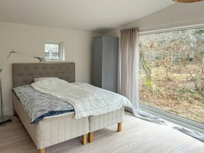 Ein Schlafzimmer mit Bett, Fenster, Kleiderschrank und Stehlampe.