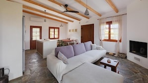 Una sala de estar con sofá, televisor, chimenea y piso de piedra.