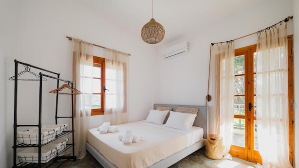 Un dormitorio con cama, armario, lámpara colgante y ventana con cortinas.