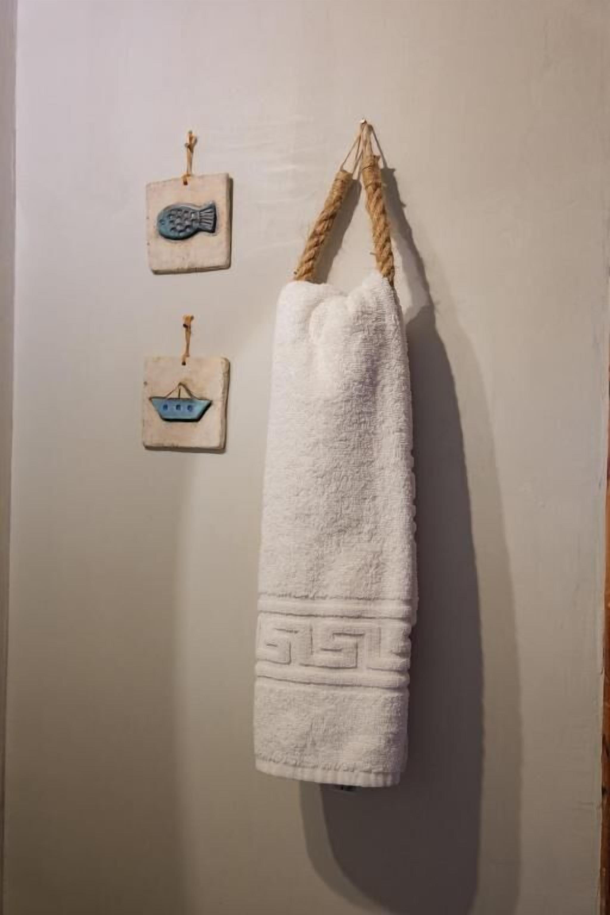 Une serviette blanche est suspendue à une corde contre un mur, et deux petits objets décoratifs sont placés en dessous.