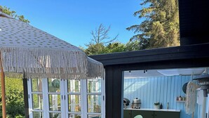 Um terraço com pérgola, cadeiras vermelhas e uma mesa.