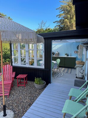 Eine Terrasse mit einer Pergola, roten Stühlen und einem Tisch.