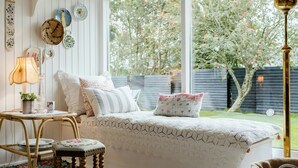 Um quarto aconchegante com uma cama, uma mesa com abajur e uma janela com vista para árvores.