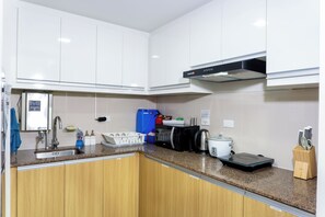Eine moderne Küche mit weißen Schränken, einer Edelstahl-Spüle, einer Kaffeemaschine und einem Wasserkocher.