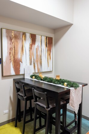A dining area with a dark wooden table, three chairs, and a large abstract painting on the wall. - 65sqm 2-bedroom condo with washer in Makati City (Makati City)