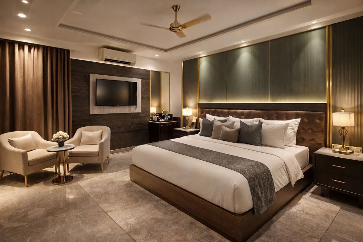 Una habitación de hotel moderna con una cama grande, un televisor, un ventilador de techo y un área de estar con dos sillones.
