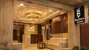 A hotel entrance with a reception desk, a chandelier, and a sign for 'Sky Suites.' - NH Skye Suites Hotel  (New Delhi)