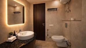 A modern bathroom with a large mirror, a sink, a toilet, and a shower. - NH Skye Suites Hotel  (New Delhi)