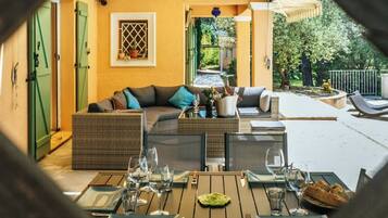 Un espace extérieur aménagé avec un canapé, une table à manger et des chaises, un pot de fleurs et une vue sur le jardin.