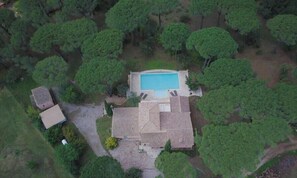 Eine Luftaufnahme einer Anlage mit Swimmingpool, einem großen Haus und umliegenden Bäumen.