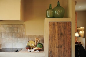 A kitchen with a stone backsplash, a wooden cabinet, and a countertop with various kitchen items.