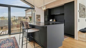 A modern kitchen with a large island, bar stools, and a view of the countryside. - Summer house by Mols Bjerge Trail with sea view (Knebel)