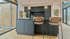 A modern kitchen with a black island, two bar stools, pendant lights, and a large window. - Summer house by Mols Bjerge Trail with sea view (Knebel)