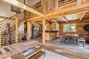 Ein Holzblock-Interieur mit Küche, Essbereich und einer Treppe.