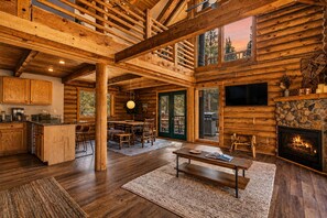 Ein Blockhaus-Interieur mit Essbereich, Küche und Kamin.