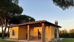 A two-story house with a patio, a chimney, and a door. - Private villa among pine trees and lavender (Marina Di Grosseto)