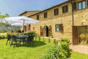 A stone building with a patio area featuring outdoor seating and umbrellas. - Apartment in the heart of Chianti with pool (Montaione)