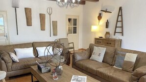 A living room with two brown leather sofas, a wooden coffee table, and a chandelier.