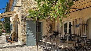 An outdoor patio with a table and chairs, a stone building, and a tree.