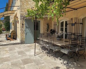 An outdoor patio with a table and chairs, a stone building, and a tree. - Provençal mansion in the heart of Luberon (Murs)