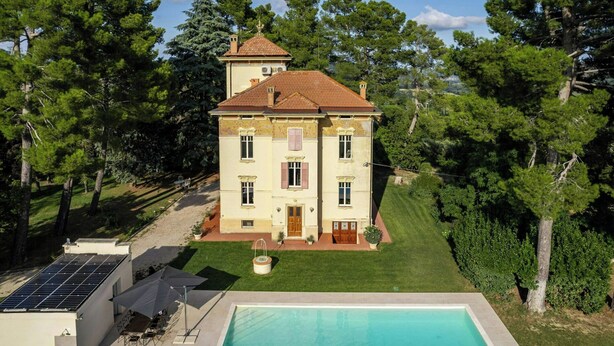 Una casa de dos pisos amb una piscina, envoltada d'arbres.